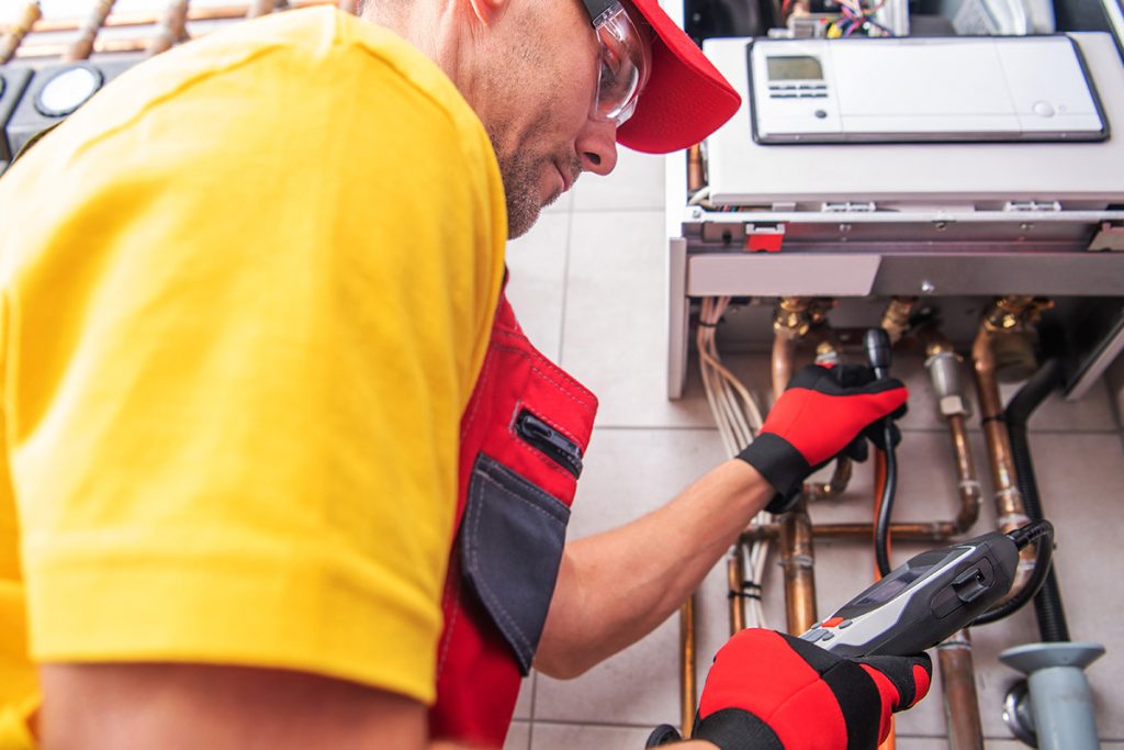 Professional Plumber Checking Water Heating System for Gas Leaks
